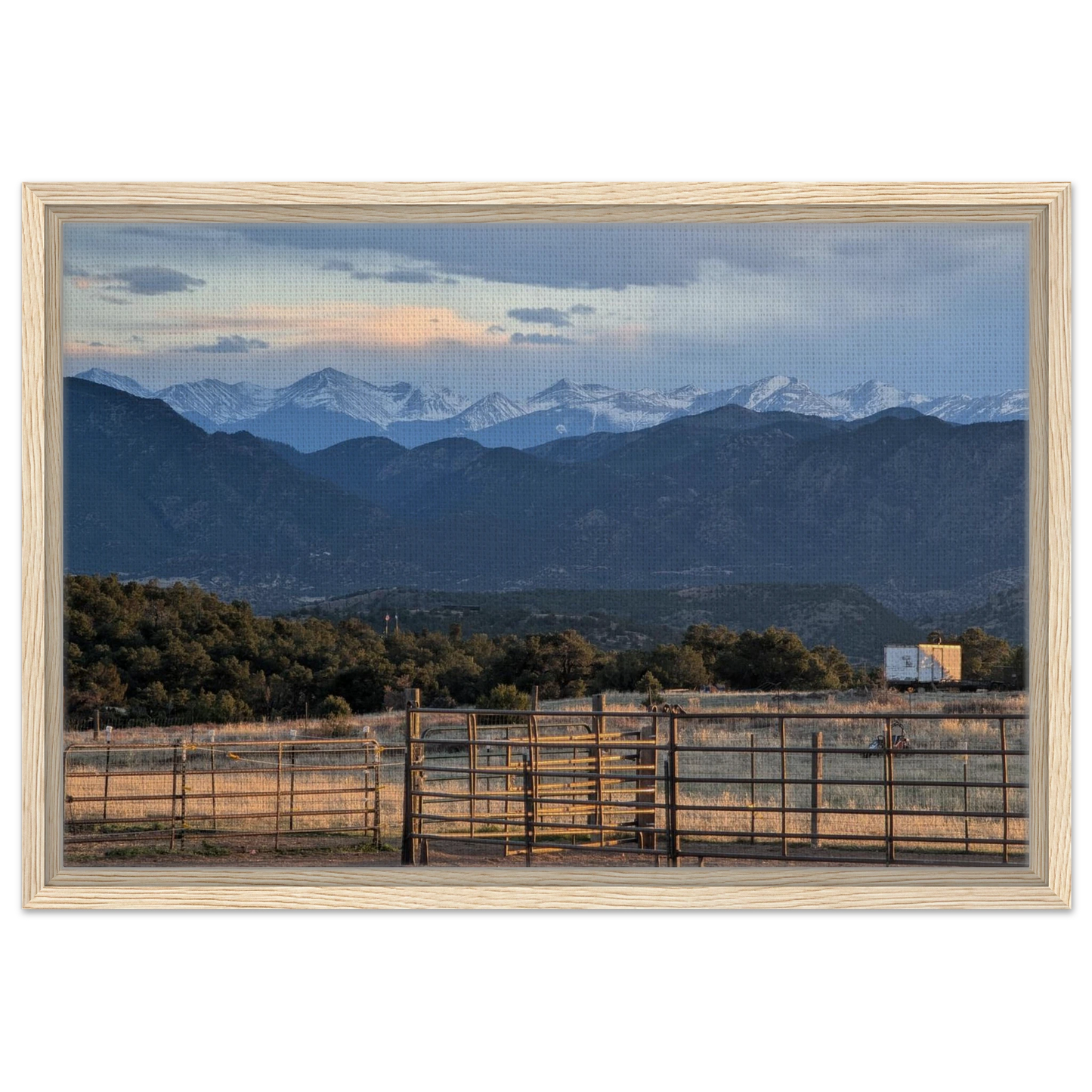 Ranch gate and fencing beneath snow-capped Rocky Mountains in warm evening light as canvas wall art.