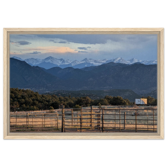 Ranch gate and fencing beneath snow-capped Rocky Mountains in warm evening light as canvas wall art.