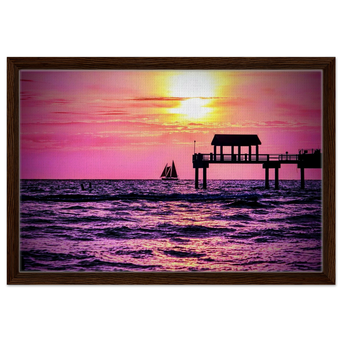 Silhouetted sailboat sailing at sunset near Clearwater Beach with vibrant pink and golden skies reflected across the Gulf waters.